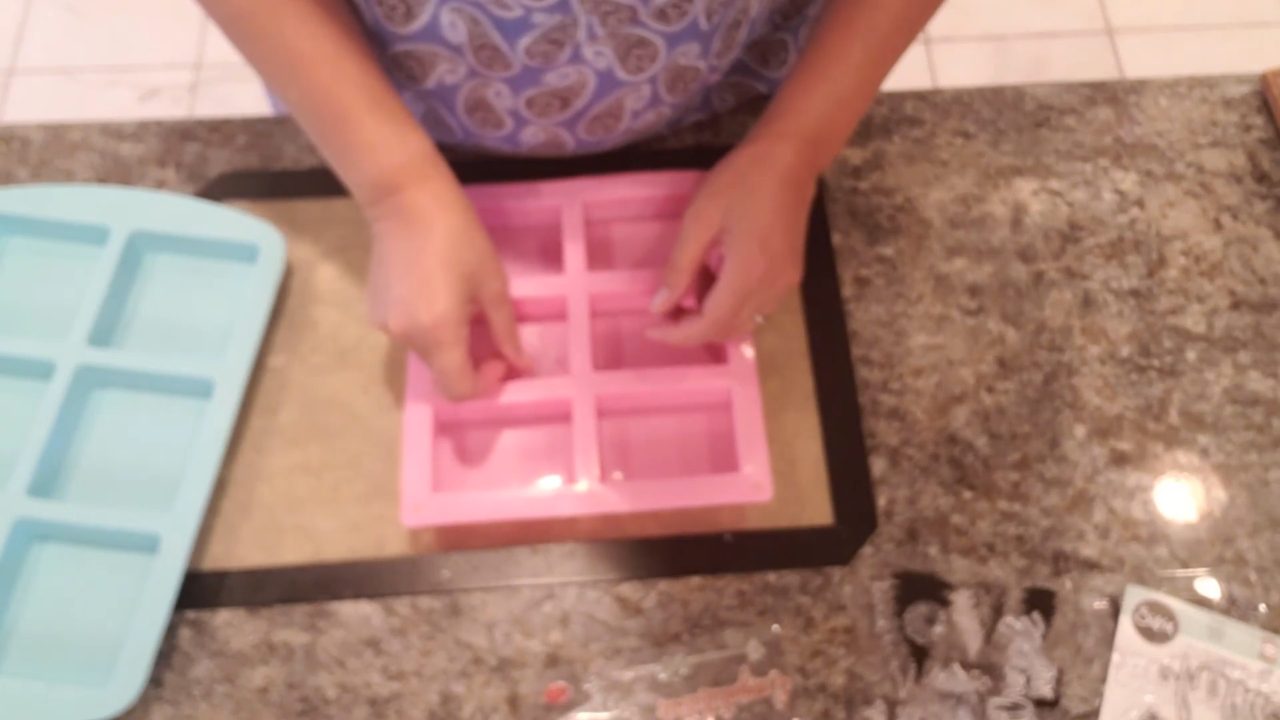Placing clear silicone stamps in the bottom of a pink soap mold