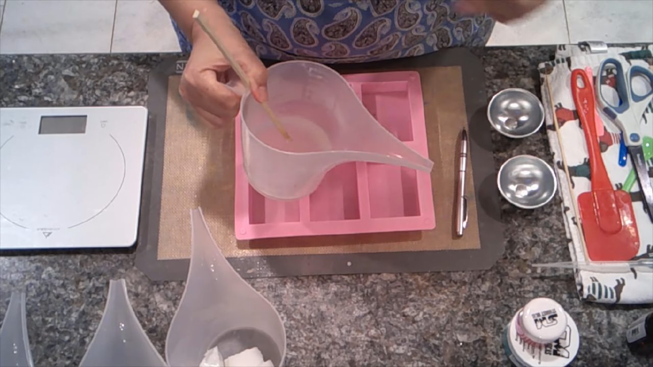 Pouring a thin layer of crystal clear soap into a pink rectangle mold