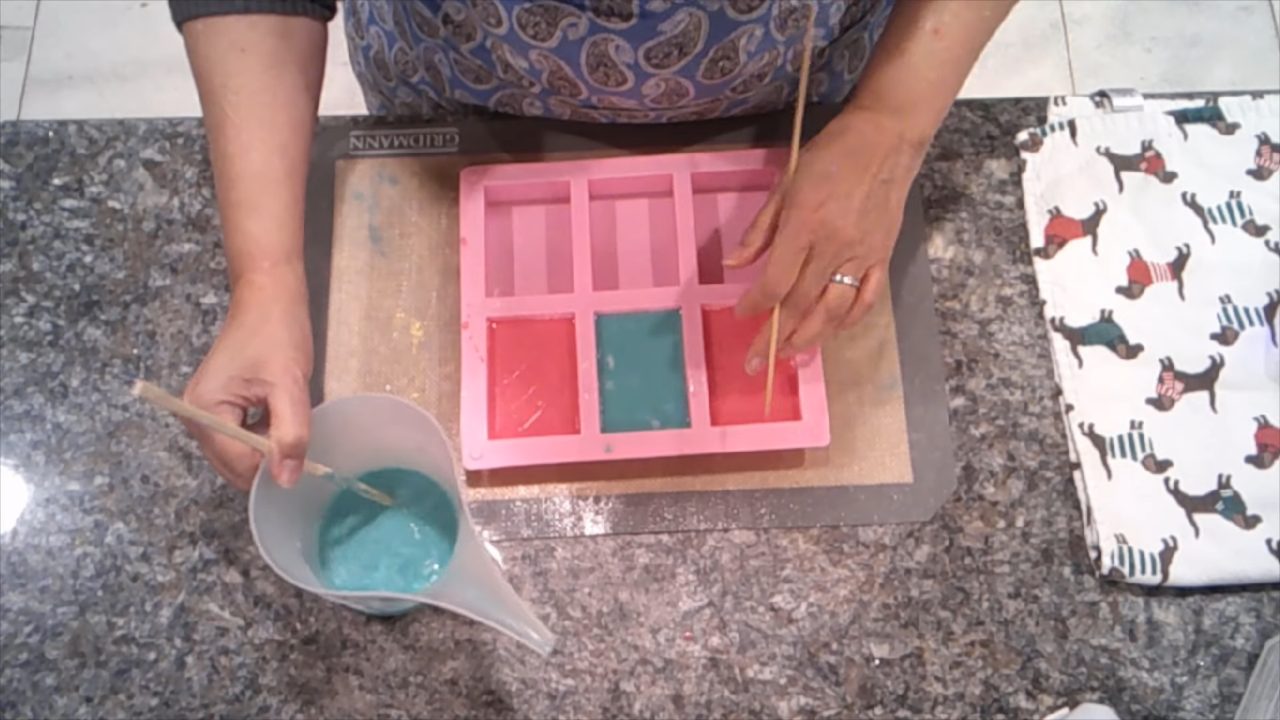 Pouring green soap to finish the back of the picture soaps