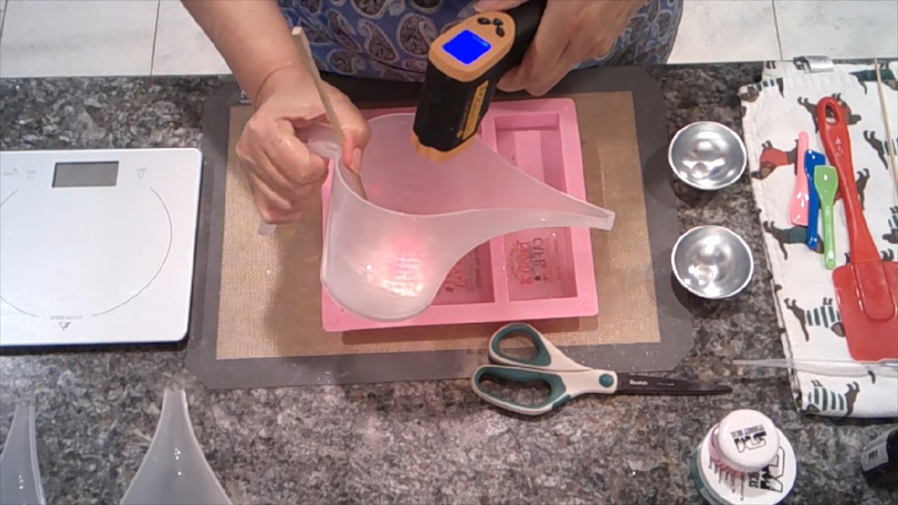 Pouring white shea butter soap behind the pictures