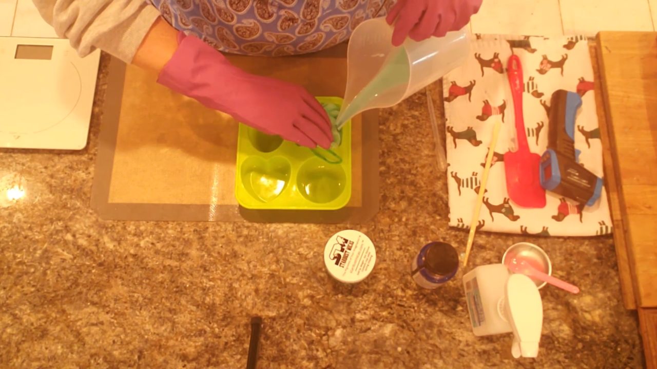 Filling the mold with green soap around the shower sponge while holding the rope out