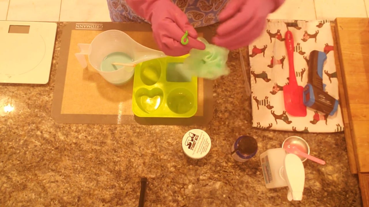 Pushing a shower sponge on a rope into melted soap in the mold