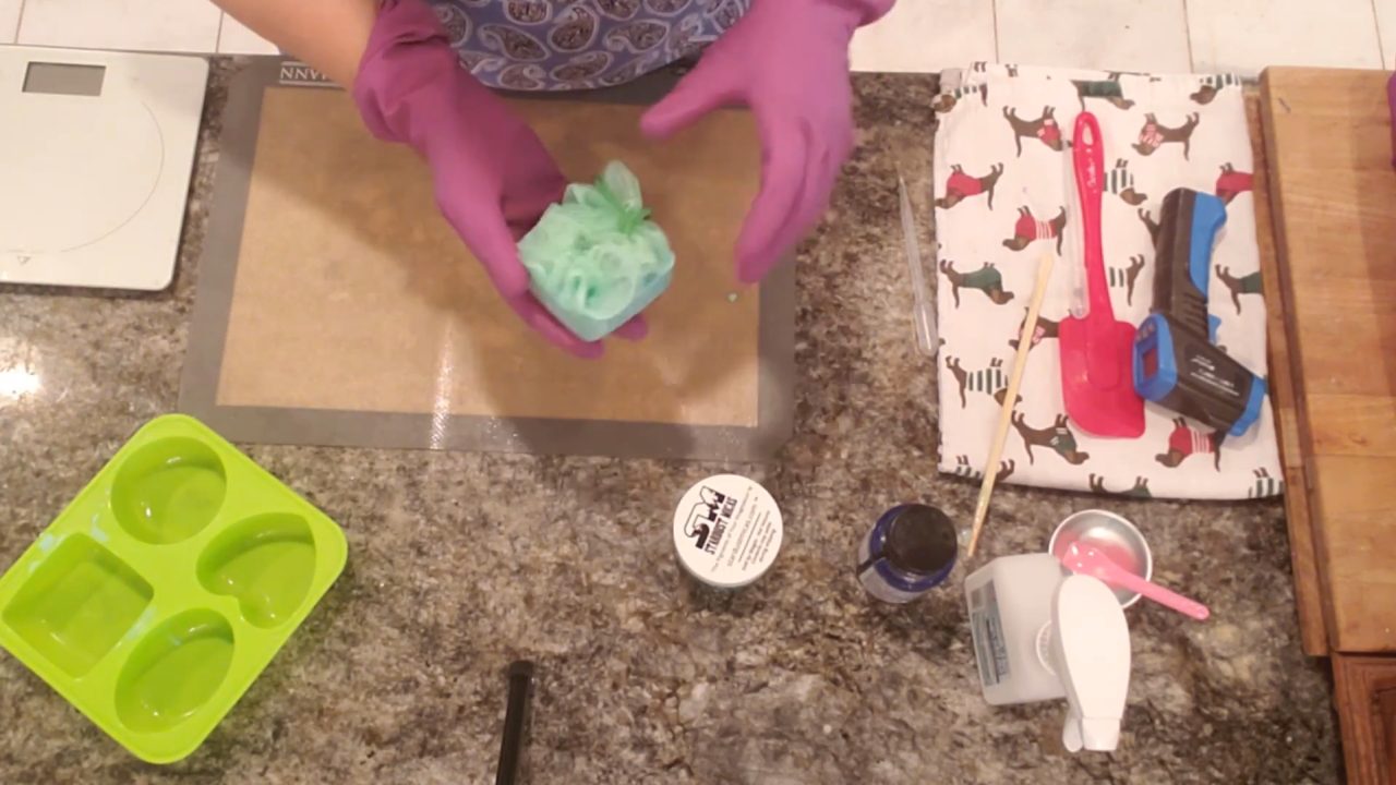 Unmolding a green soap on a rope with a shower sponge