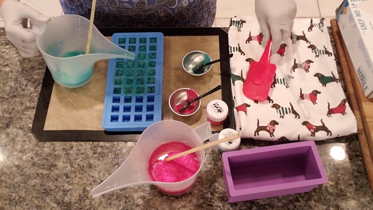 Pouring green clear soap into a small square silicone mold