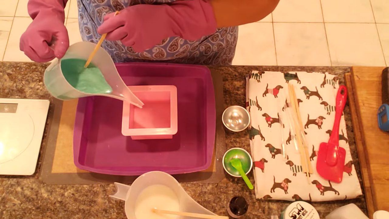 Pouring a green bottom layer of soap into a square mold
