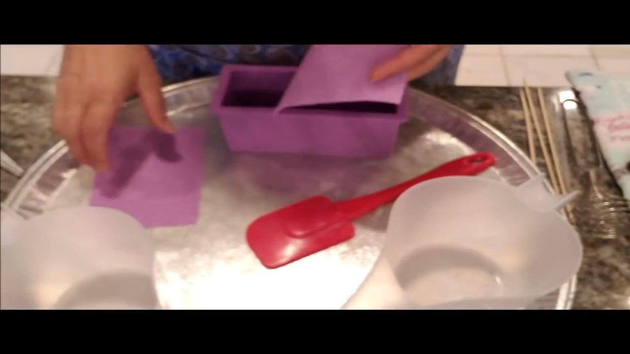 Gluing an impression mat inside a mini loaf soap mold with melted soap