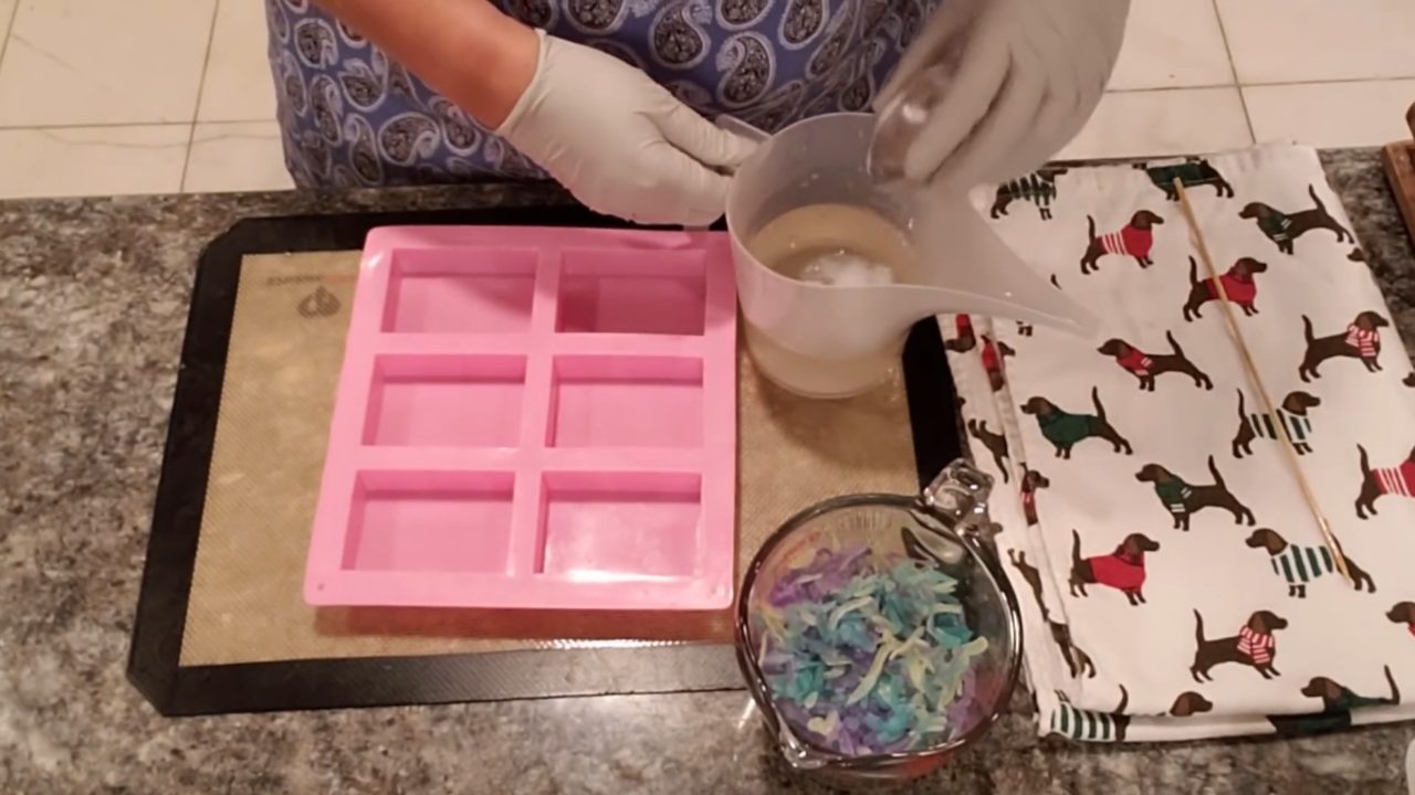 Melted crystal clear soap base with bio glitter next to a bowl of soap shavings