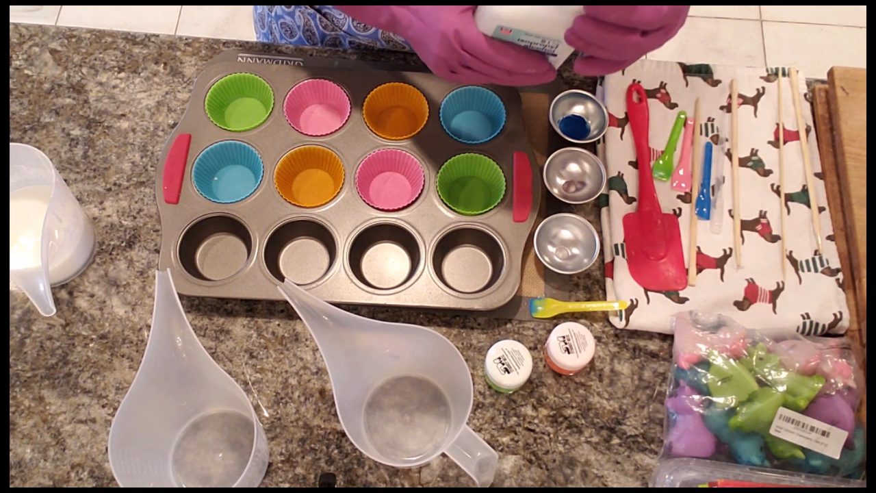 Pouring neon blue shea butter soap into silicone cupcake liners in a muffin pan
