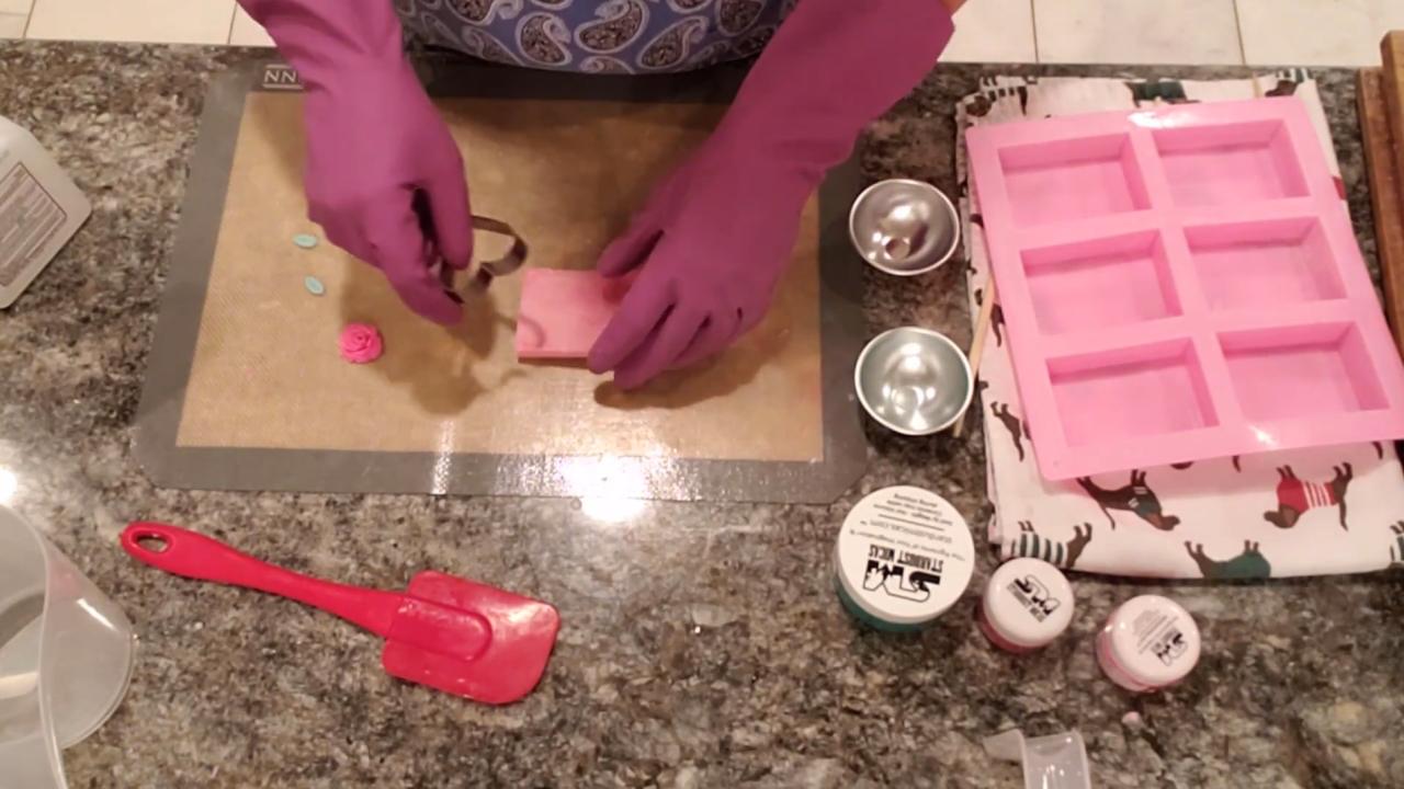Cutting a heart out of the pink soap bar with a cookie cutter