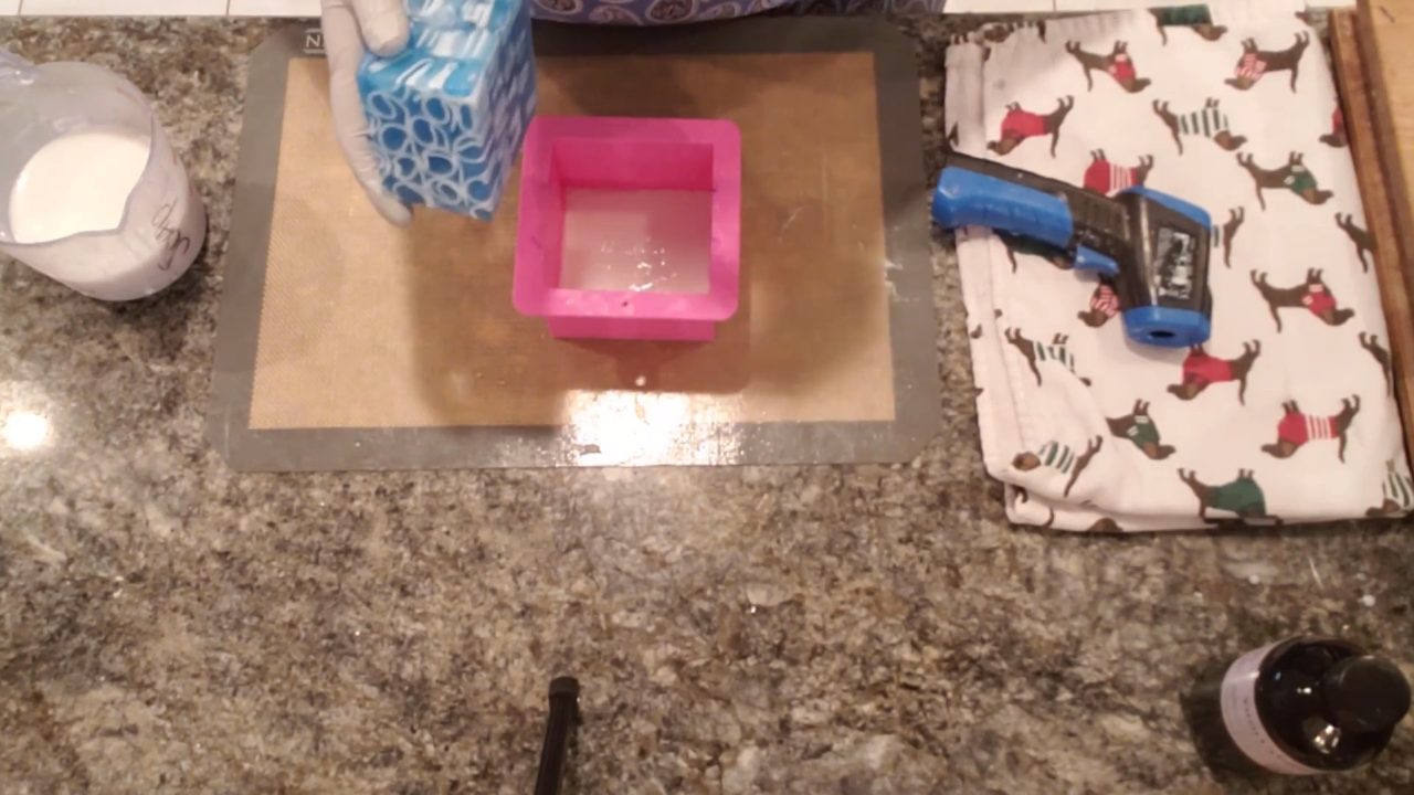 Blue soap curl insert centered in a mold with shea butter soap around it