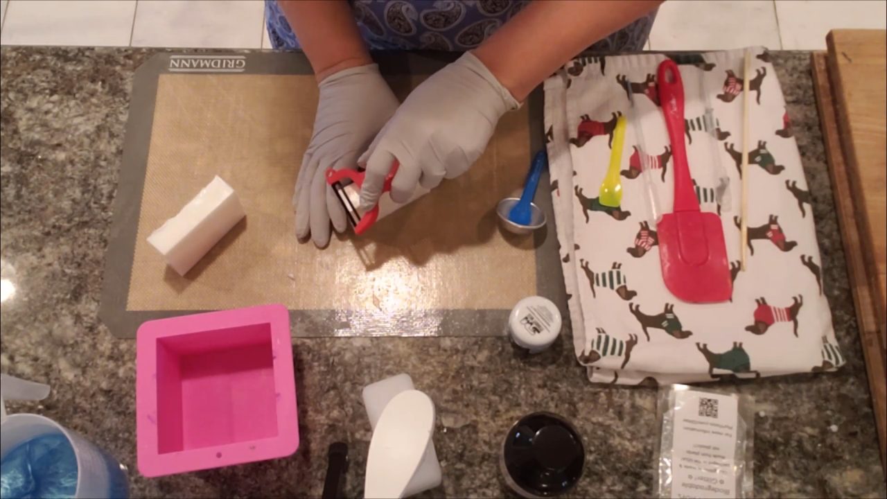 Peeling soap curls from a shea butter bar with a potato peeler