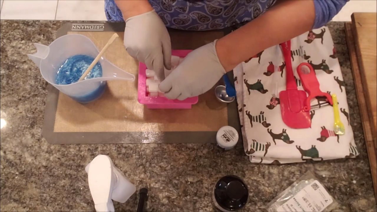 Pouring blue clear melt and pour soap over the soap curls